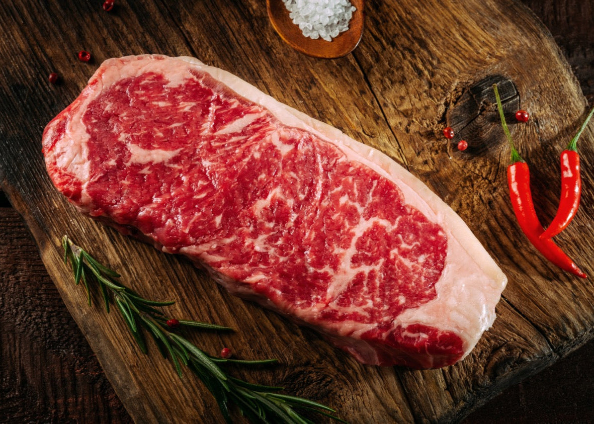 Raw Irongate sirloin on a wooden cutting board with spices and herbs