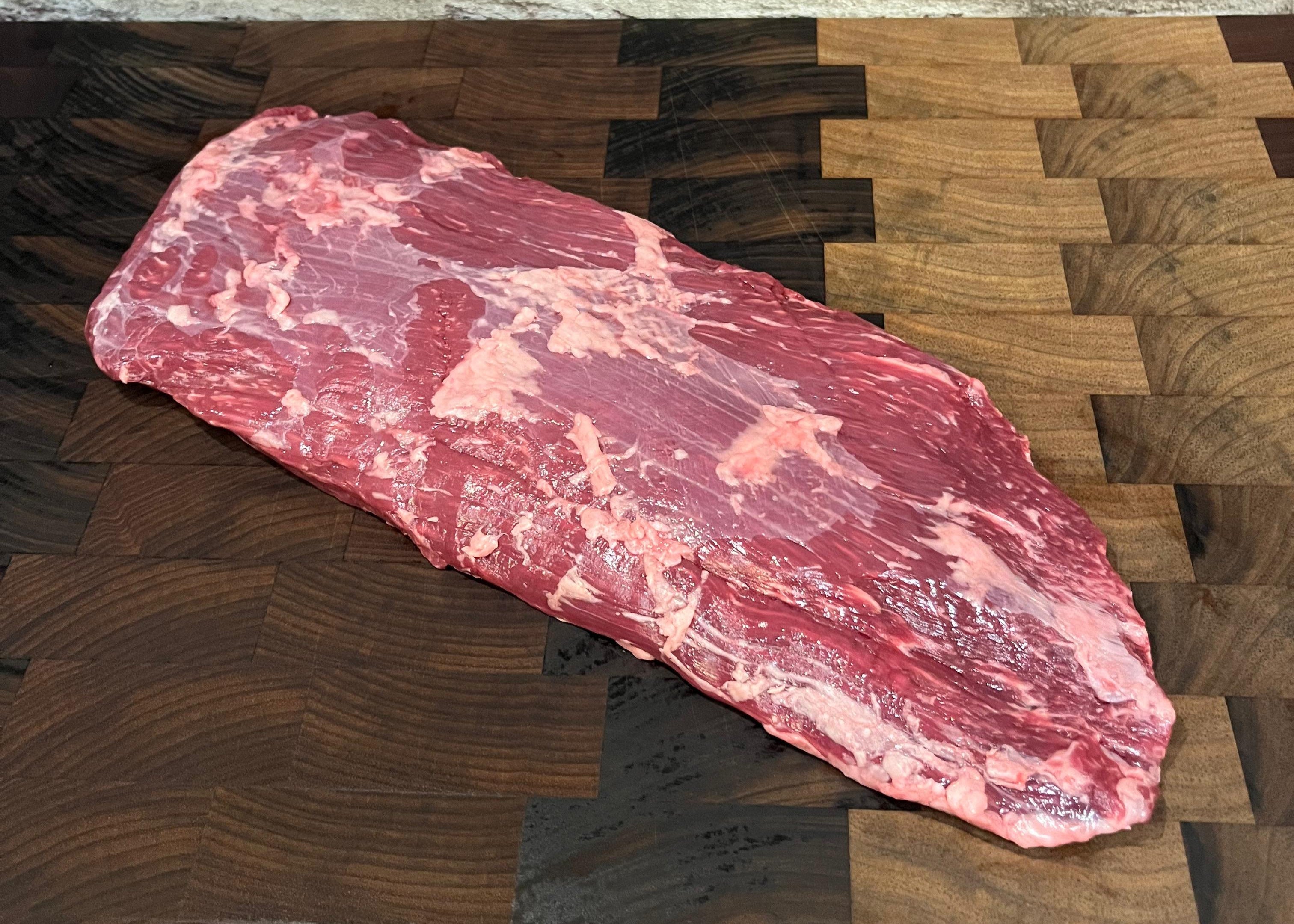A Wagyu Sierra steak on a wooden cutting board.